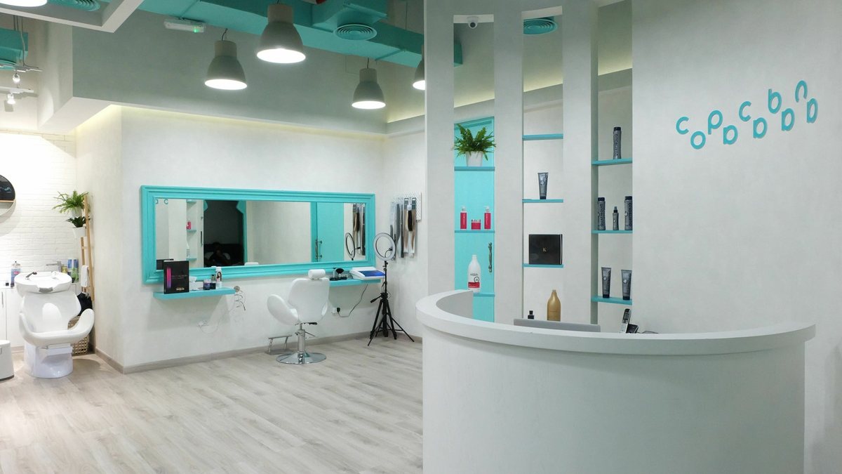 Inside the salon: white reception curve, turquoise mirror frames and product shelves