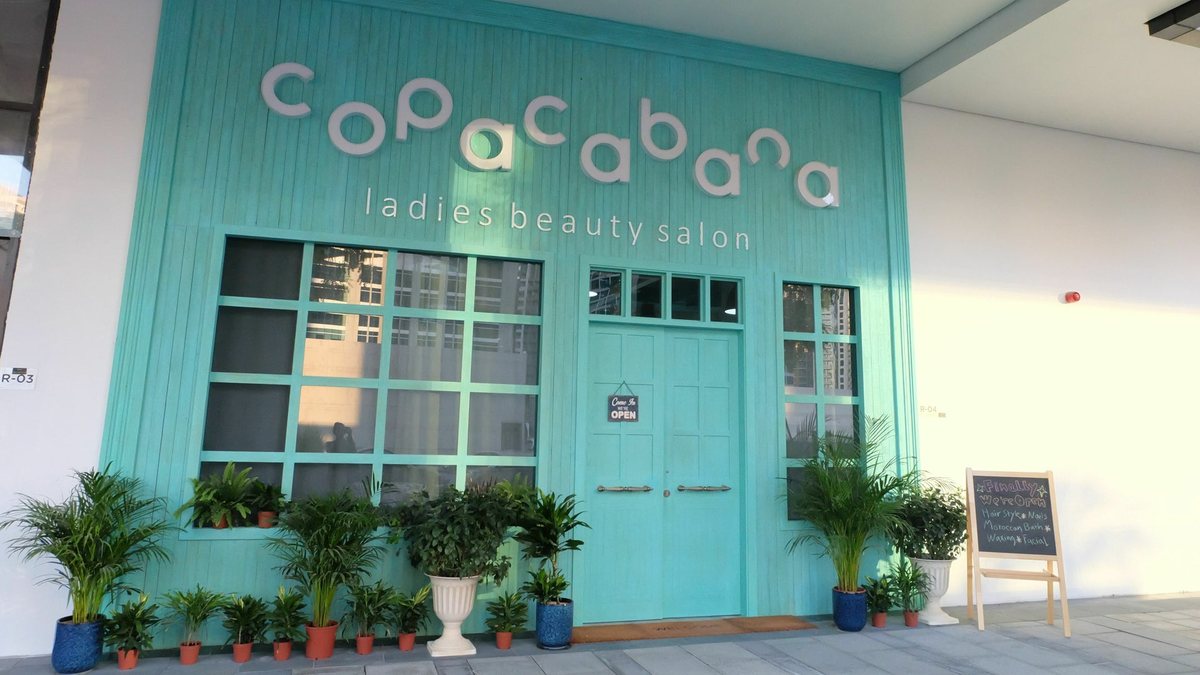 The turquoise painted beach-house facade of Copacabana with white lettering and potted palms