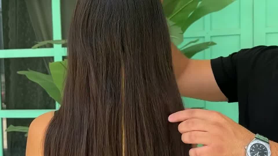 A stylist checking the length of a client's long hair in front of the turquoise Copacabana storefront